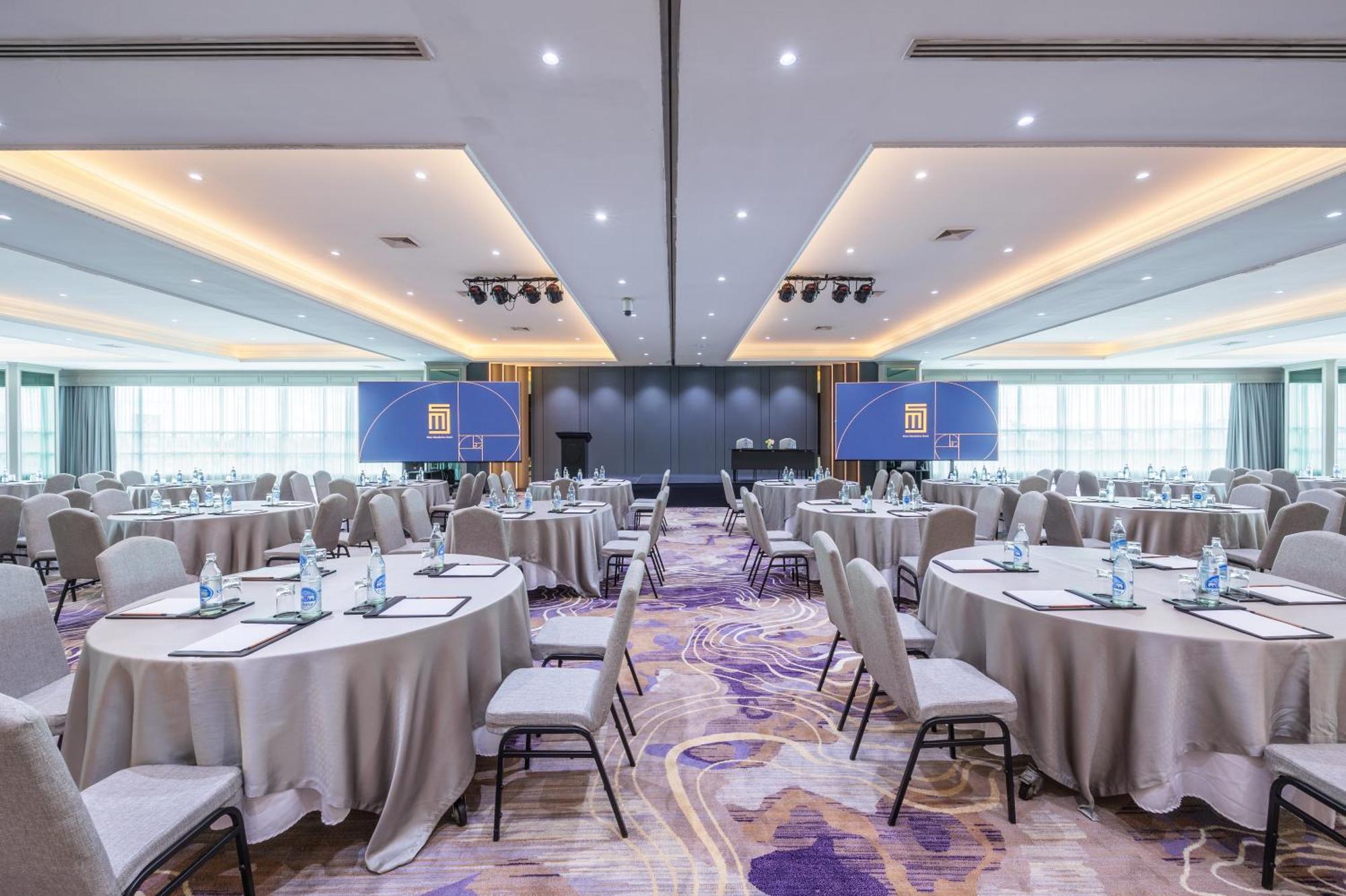 סאמוט פראקאן Siam Mandarina Hotel - Free Bkk Airport Shuttle מראה חיצוני תמונה The photo shows a modern conference room set up for an event. There are several round tables, each covered with a light-colored tablecloth, and accompanied by chairs. On each table, there are bottles of water, notepads, and pens. The room is well-lit