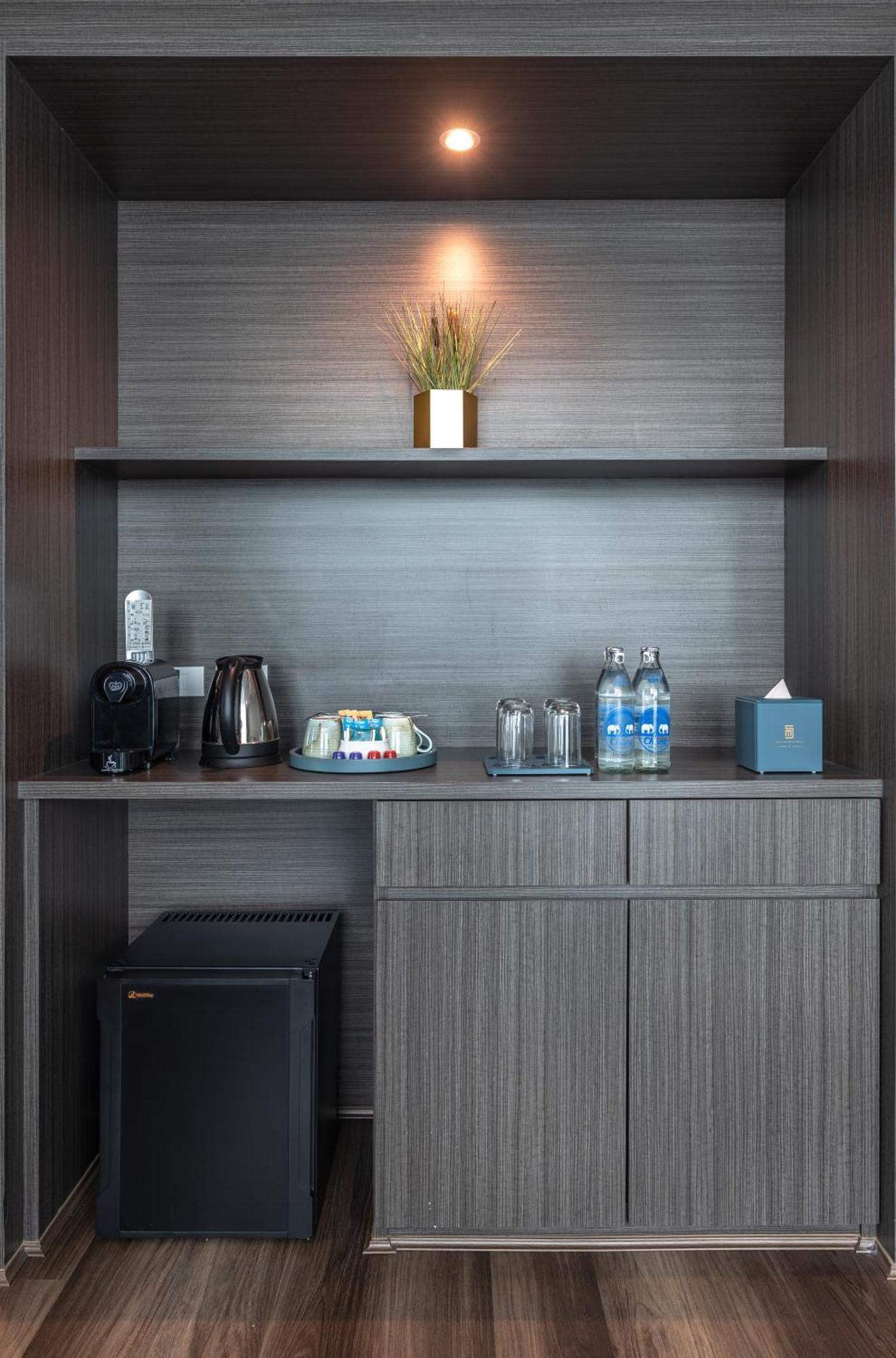 סאמוט פראקאן Siam Mandarina Hotel - Free Bkk Airport Shuttle מראה חיצוני תמונה The photo shows a modern kitchenette or mini-bar area. It features a dark wooden shelf with a small plant in a pot for decoration. On the shelf, there is an electric kettle, a coffee machine, several cups, and two glass containers for drinks. Additio