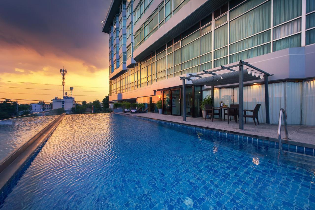 סאמוט פראקאן Siam Mandarina Hotel - Free Bkk Airport Shuttle מראה חיצוני תמונה The photo shows a luxurious hotel with a large swimming pool in the foreground. The pool features a clear blue water surface, reflecting the warm colors of a sunset in the sky. In the background, the hotel has a modern design with numerous large wind